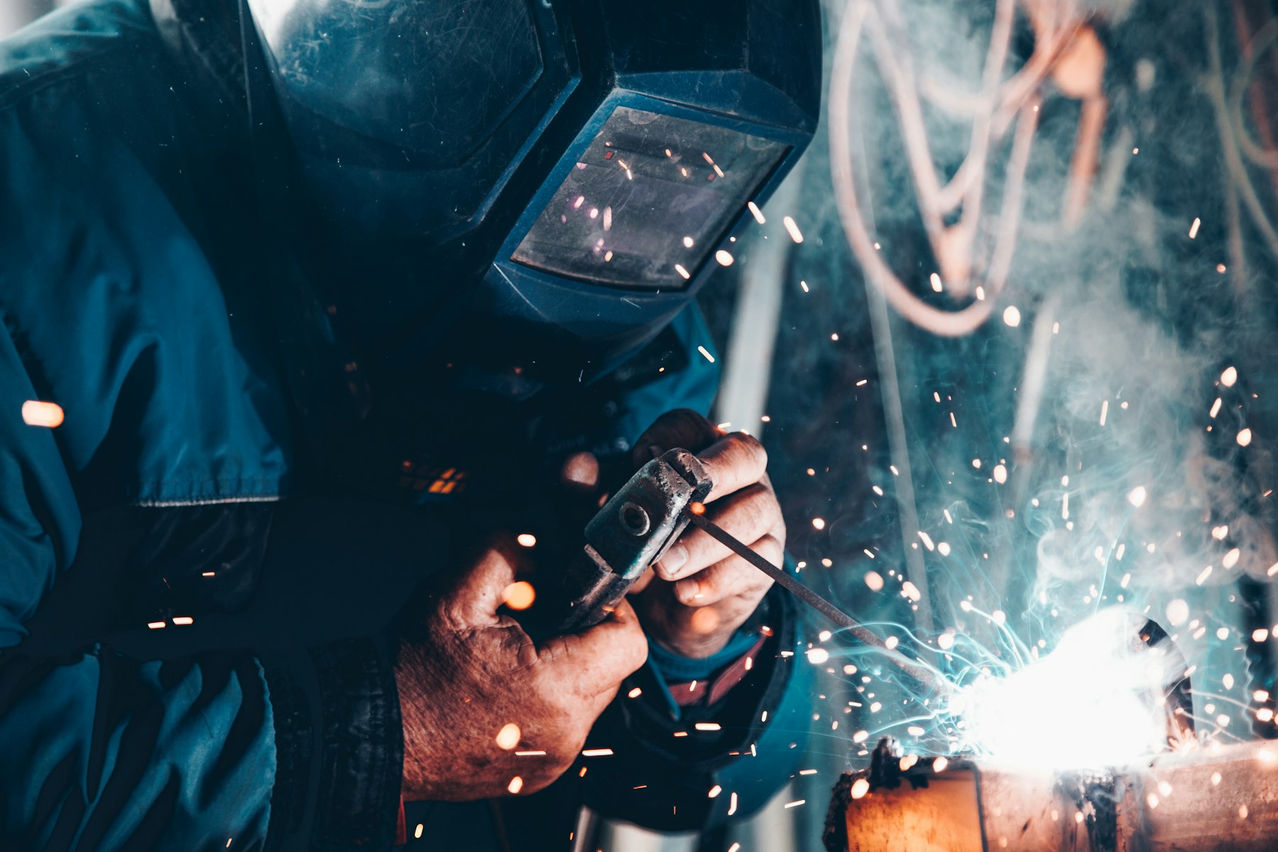 Welder joining pipe amid sparks
